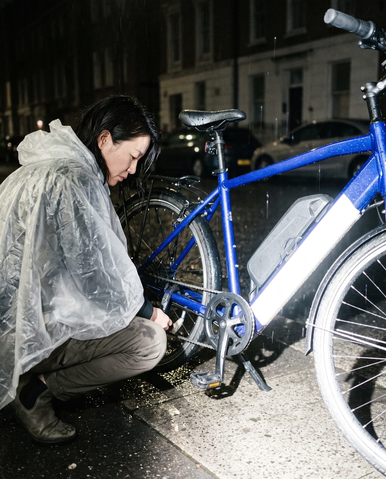 Blue e-bike in the rain, a cyclist crouching