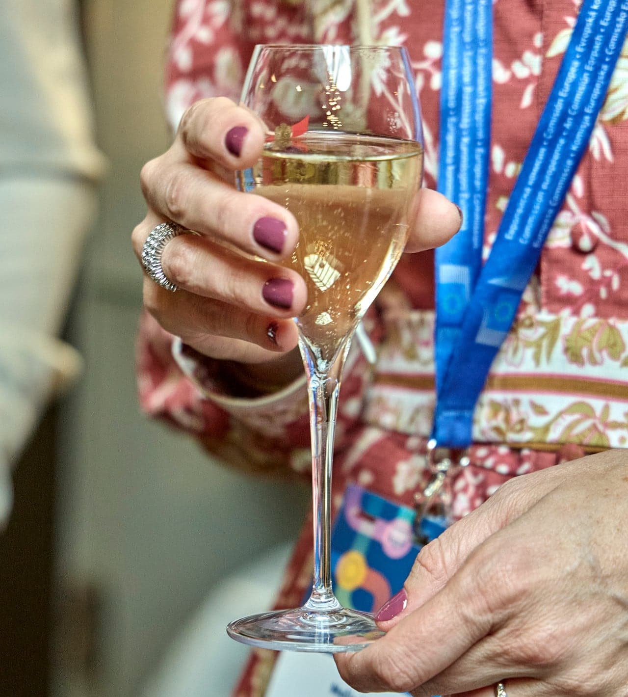 A guest holding a glass of champagne, IPSW lanyard around the neck