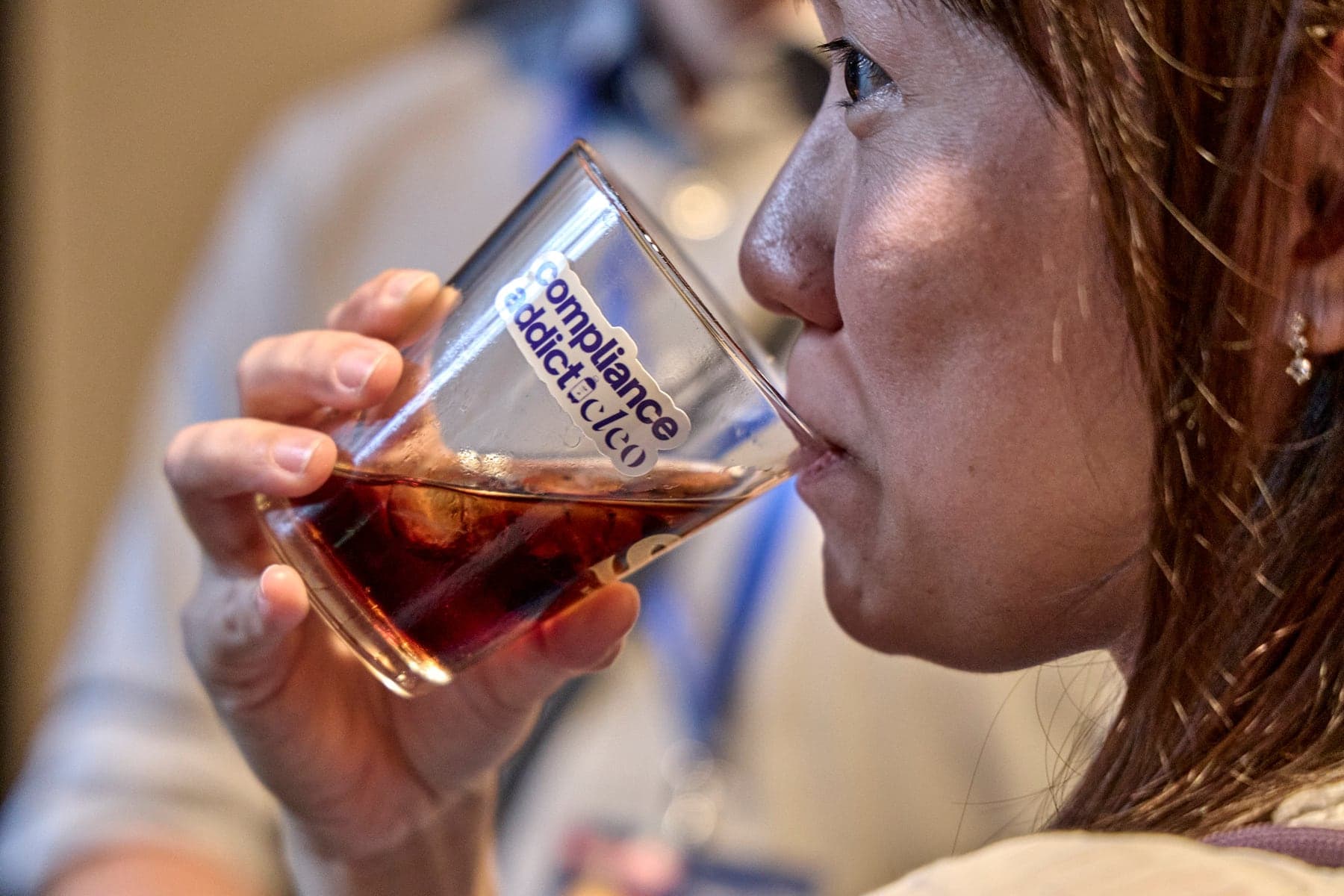 A guest drinking from a glass marked Compliance addict by Cleo