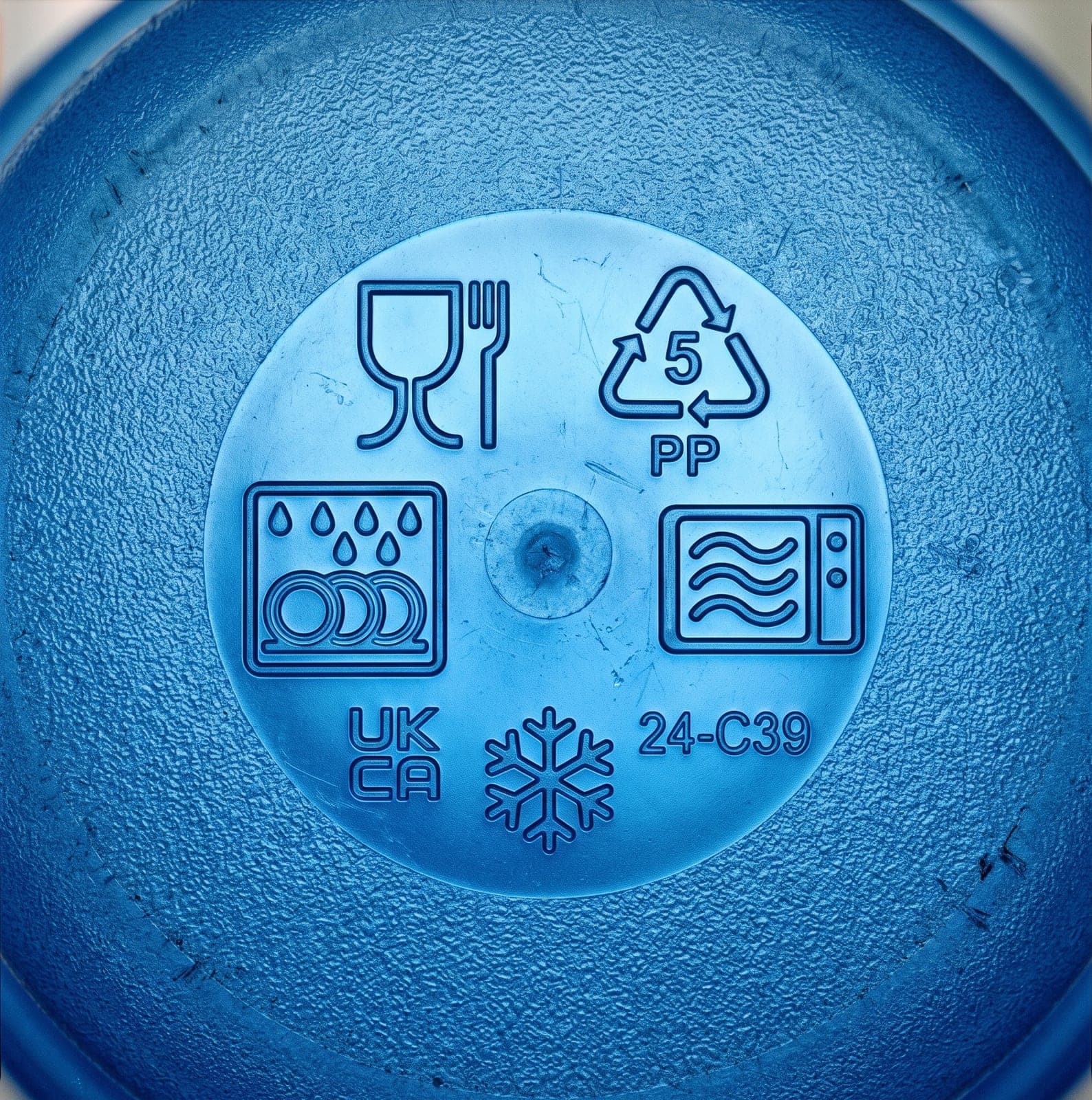 Gros plan sur le dessous d'une boîte alimentaire en plastique bleu translucide, symbole verre et fourchette, triangle de recyclage