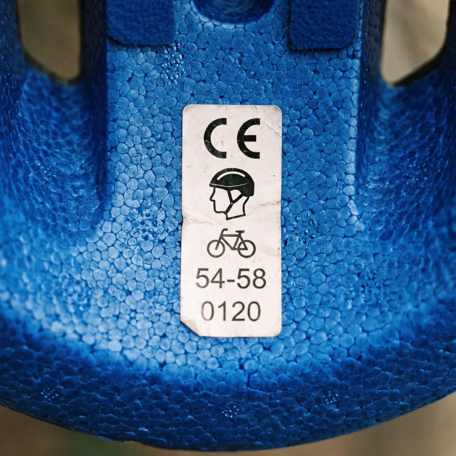 Gros plan sur l'intérieur en mousse bleue d'un casque de vélo, étiquette avec marquage CE, pictogrammes et tailles